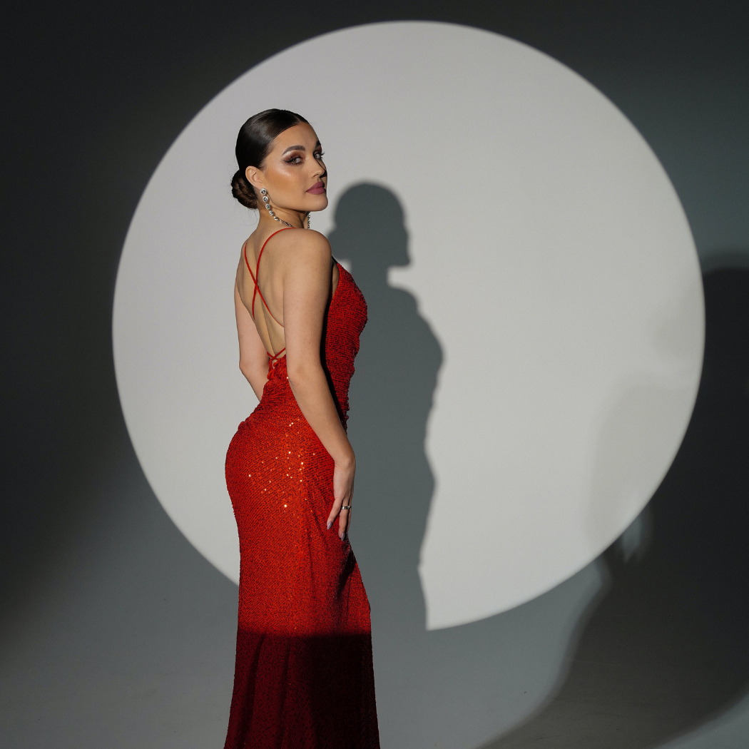 Frau im roten glitzernen Designerkleid im Scheinwerferlicht